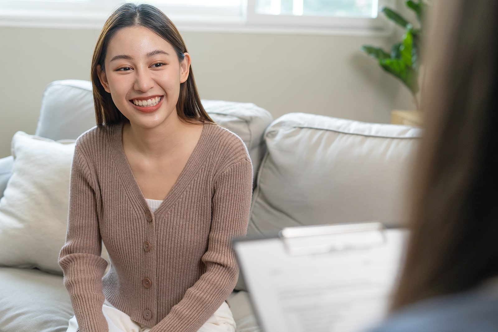 Image of a smiling woman sitting on a couch speaking with a therapist